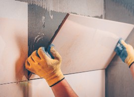 placing a tile on a wall covered with tile adhesive