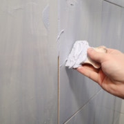 pre-mixed grout being applied to grey wall tiles